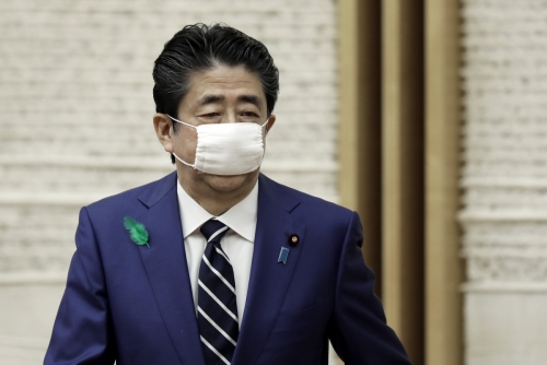 ▲아베 신조 일본 총리가 17일 언론 브리핑을 마치고 사이즈가 적은 마스크를 쓴 채 떠나고 있다. 도쿄/AP연합뉴스
