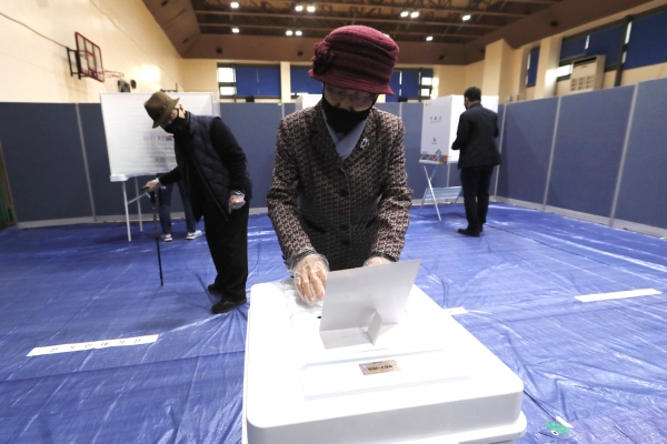▲서울의 한 투표소에서 15일 총선이 진행 중인 가운데 마스크를 쓴 한 여성이 표를 투표함에 넣고 있다. 코로나19 팬데믹 와중에 세계에서 처음으로 치러지는 선거라는 점에서 주요 외신이 이날 총선에 비상한 관심을 보이고 있다. 서울/AP연합뉴스 
