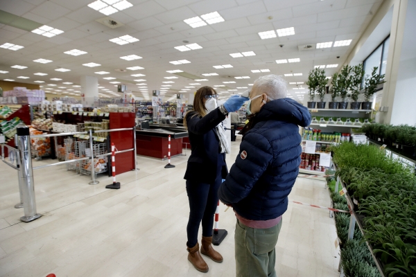 ▲이탈리아 밀라노의 한 슈퍼마켓에서 3월 25일(현지시간) 종업원이 고객 체온을 재고 있다. 밀라노/AP뉴시스
