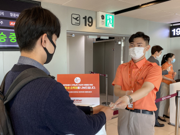 ▲제주항공 직원이 김포공항 제주항공 탑승구에서 탑승객들에게 손소독제를 나눠주고 있다.  (사진제공=제주항공)