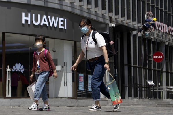 ▲중국 베이징의 한 화웨이 매장 앞을 18일(현지시간) 주민이 마스크를 착용한 채로 지나가고 있다. 베이징/AP뉴시스 
