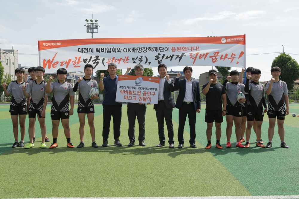 ▲지난 3일 대전 가양중학교 열린 ‘럭비 월드컵 공인구 및 마스크 전달식’ 후 이원용 가양중학교 럭비부 감독(왼쪽 여섯번째부터), 남동균 대전시럭비협회장, 탁용원 OK금융그룹 스포츠단장, 신행돈 대전지부장 등 참석자들이 기념 촬영하고 있다. (사진제공=OK금융그룹)