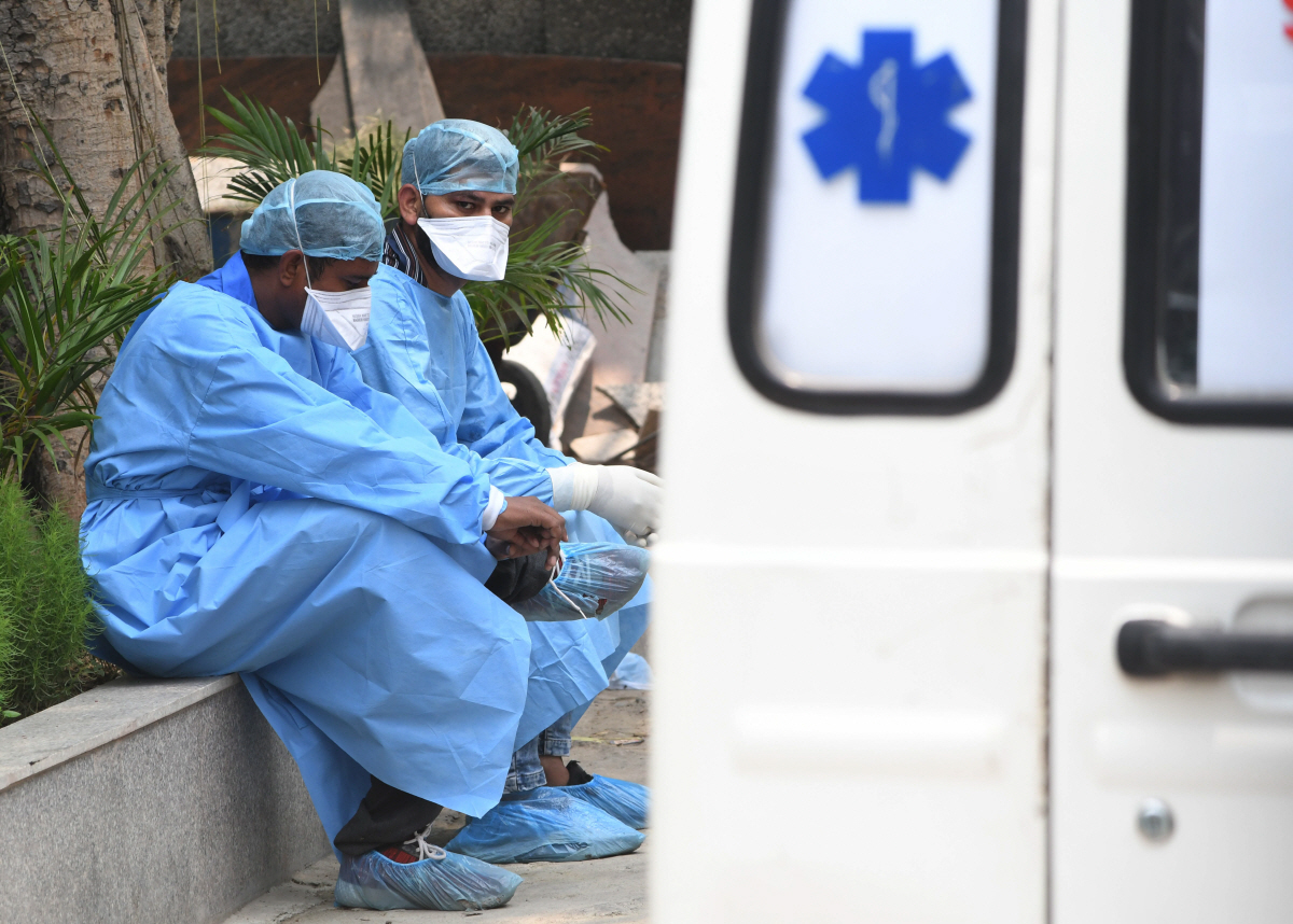 ▲인도 뉴델리의 코로나19 사망자 전용 장례식장에서 13일(현지시간) 가족을 잃은 사람들이 개인방호복을 입은 채로 앉아 있다. 뉴델리/EPA연합뉴스