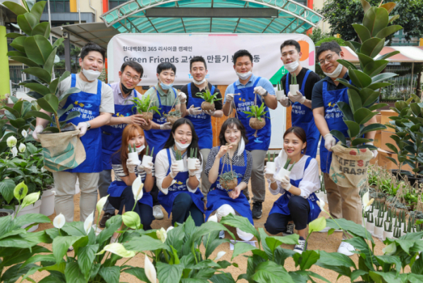 ▲18일 오후 서울 구로구 매봉초등학교에서 현대백화점 직원들이 공기정화식물과 함께 기념 촬영을 하고 있다. (사진제공=현대백화점)