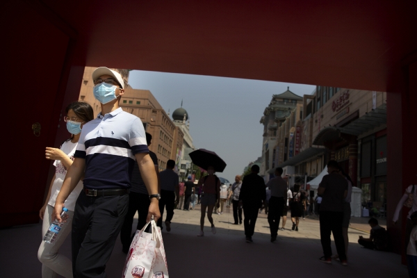 ▲6일 중국 베이징에서 마스크를 쓴 시민들이 소비자 수요 및 소비 촉진을 겨냥한 정부 행사에서 걸어가고 있다. 베이징/AP연합뉴스
