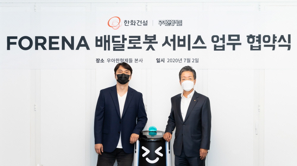 ▲윤용상(오른쪽) 한화건설 건축사업본부장과 윤현준 우아한형제들 부사장이 2일 송파구 방이동 우아한형제들 사옥에서 '포레나 배달로봇 서비스 업무협약' 체결 후 기념촬영을 하고 있다. (사진 제공=한화건설)