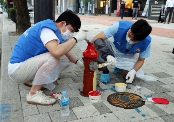 ▲KCC 행복나눔 봉사단 직원들이 서초구 뱅뱅사거리 인근 소화전에 색을 칠하고 있다. (사진제공=KCC)