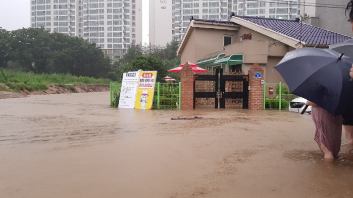 ▲2일 오전 내린 집중 호우로 충북 제천시의 주택들이 침수됐다. 물이 무릎까지 차오른 도로에서 주민들이 걱정스럽게 주택을 바라보고 있다. (연합뉴스)
