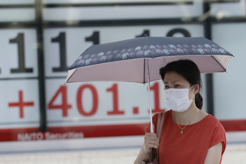 ▲일본 도쿄에서 3일(현지시간) 마스크를 쓴 행인이 양산을 쓴 채 지나가고 있다. 도쿄/AP연합뉴스

