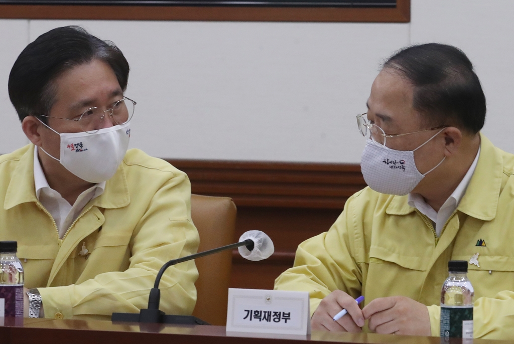 ▲홍남기 경제부총리 겸 기획재정부 장관(오른쪽)과 성윤모 산업통상자원부 장관이 14일 오전 서울 종로구 정부서울청사에서 서울-세종 화상으로 열린 코로나19 대응 중앙재해안전대책본부 회의에 참석해 이야기를 나누고 있다.  (뉴시스)