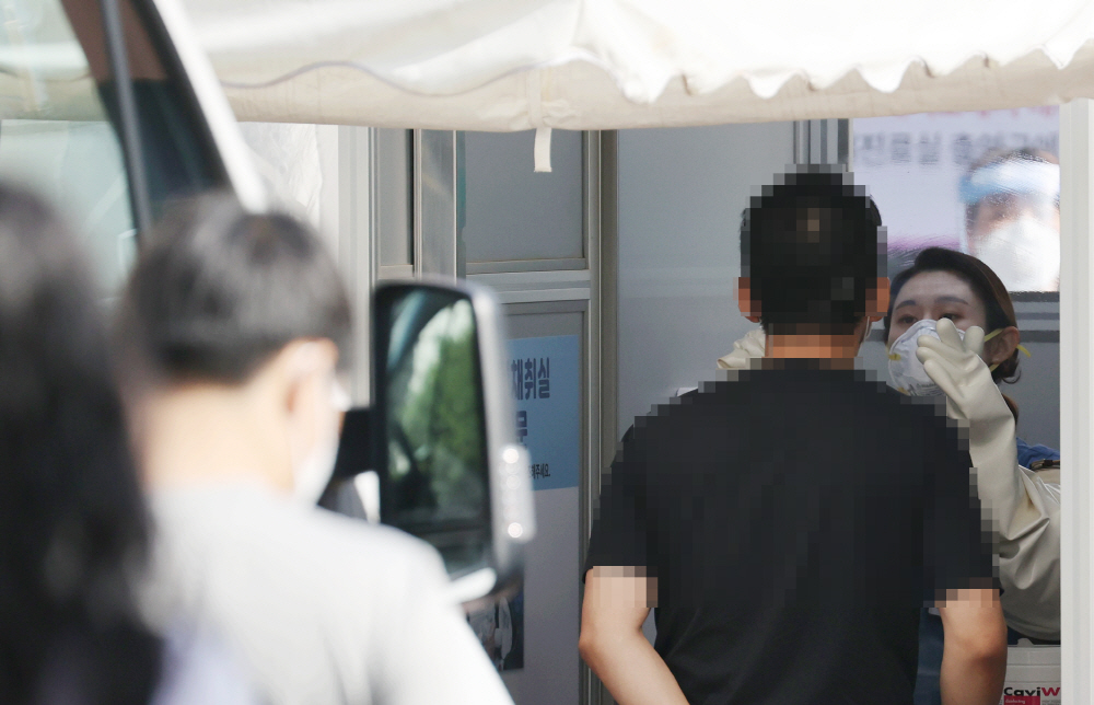 ▲25일 서울 중구 국립중앙의료원에 마련된 신종 코로나 바이러스 감염증(코로나19) 외부 검체 채취실에서 의료진이 의료용 분리벽(글로브-월)을 사이에 두고 내원객들의 코로나19 검체를 채취하고 있다. (연합뉴스)