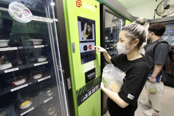 ▲KT 기가에너지 매니저 프랜차이즈 플러스가 적용된 서울 마곡나루의 '잇다가게'에서 고객들이 자판기를 이용해 비대면으로 반찬을 구매하고 있다. (KT 제공)