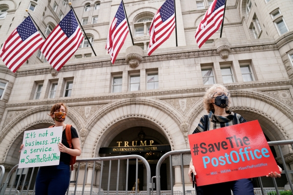 ▲마스크를 쓴 시위대가 22일(현지시간) 워싱턴D.C의 트럼프 인터내셔널 호텔 앞에서 “우체국을 지켜라”라는 플래카드를 들고 시위하고 있다. 워싱턴D.C./로이터연합뉴스
