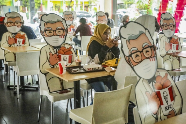 ▲4일(현지시간) 인도네시아 수마트라 메단의 KFC 매장에서 고객들이 사회적 거리 두기 유지를 위해 의자에 고정된 보드지 사이에 앉아 있다. 메단/EPA연합뉴스

