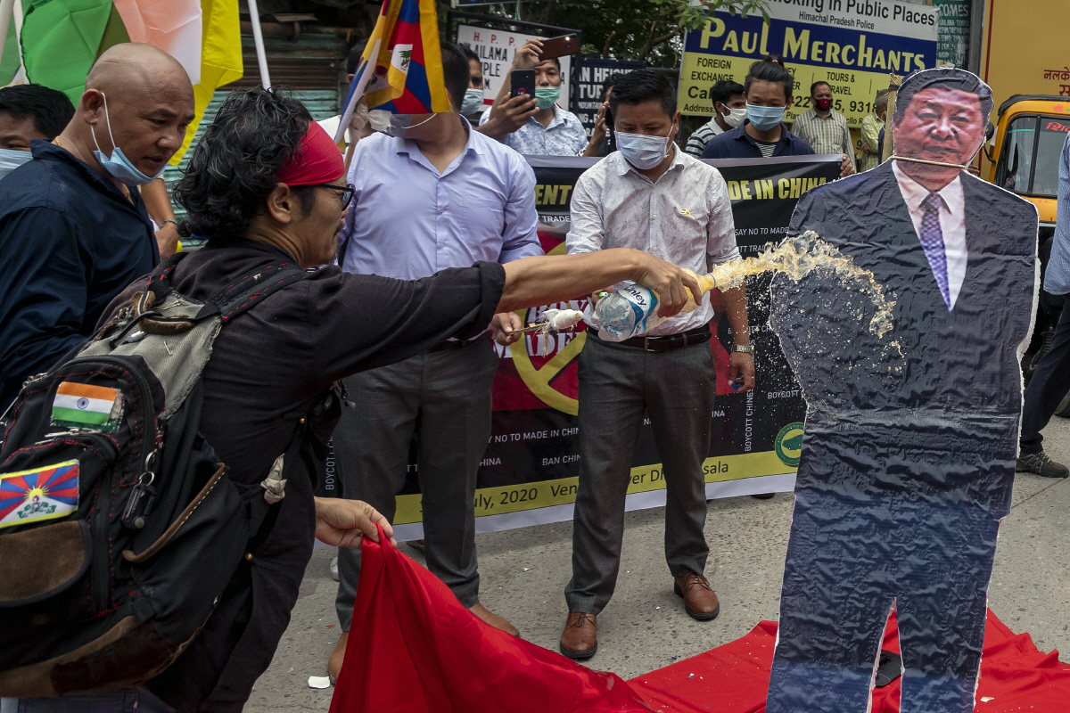 ▲인도 다람살라에서 7월 10일(현지시간) 중국 제품 보이콧 시위가 열리는 가운데 한 시위자가 시진핑 중국 국가주석 사진에 휘발유를 끼얹고 있다. 다람살라/AP뉴시스