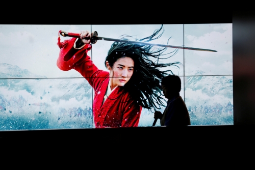 ▲중국 베이징에서 11일(현지시간) 행인이 월트디즈니의 신작 ‘뮬란’ 광고판 앞을 지나가고 있다. 베이징/로이터연합뉴스
