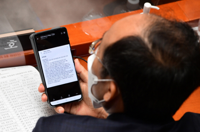 ▲국민의힘 추경호 예결위 간사가 18일 국회 예산결산특별위원회 전체회의에서 제4차 추가경정예산안에 대한 예결위 심사가 시작되기 전에 고용노동부가 보낸 '긴급고용안정지원금 2차지원' 관련 문자를 보여주며 이의를 제기하고 있다. (연합뉴스)