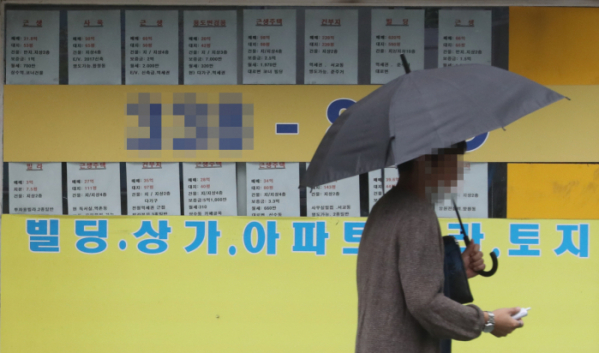 ▲주택 임대차 2법 시행 후 전세 가격이 이중화하고 있다. 같은 단지, 같은 면적이라도 전세 계약을 갱신했는지, 새로 맺었는지에 따라 전셋값이 수억 원까지 차이 나는 것이다. 서울의 한 부동산 중개업소 앞을 우산을 든 시민이 지나가고 있다. (연합뉴스)