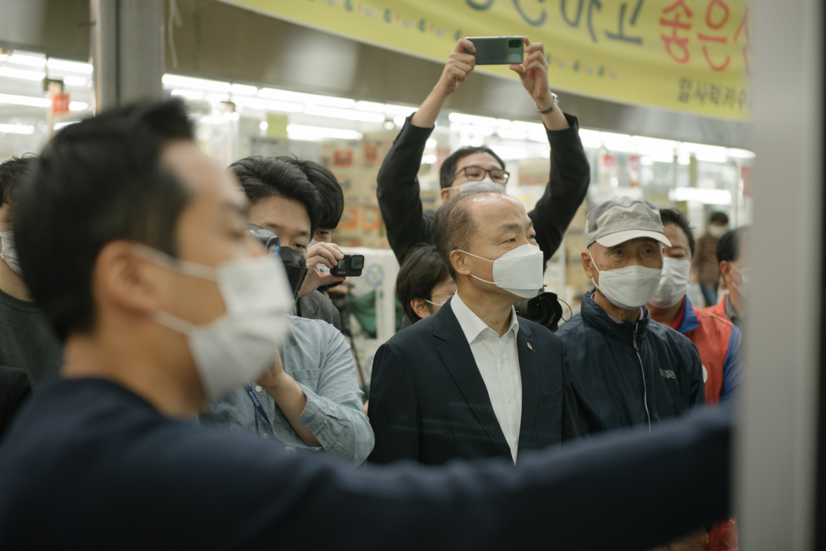 ▲조봉환 소상공인시장진흥공단 이사장(사진 가운데)이 5일 서울암사종합시장 비대면 장보기 시연회에 참석하여 온라인 접수를 통한 조리 및 포장 과정을 살펴보고 있다. (사진제공=소상공인진흥공단)