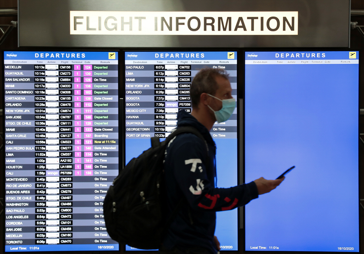 ▲한 승객이 마스크를 쓴 채 공항 비행 안내판 앞을 지나가고 있다. 사진은 기사의 특정 내용과 관계 없음. 로이터연합뉴스