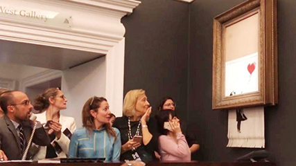 ▲런던 소더비 경매에서 낙찰된 뱅크시의 작품 ‘풍선과 소녀’가 파쇄기에 잘려나가고 있다. ⓒ Banksy