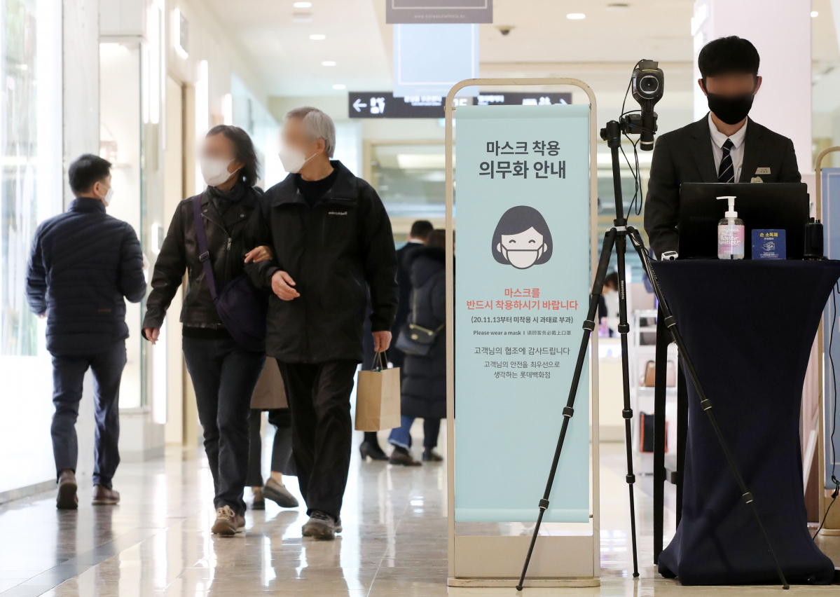 ▲마스크 미착용 단속을 하루 앞둔 12일 오전 서울 중구 롯데백화점에서 마스크 의무화 안내문 옆으로 시민들이 지나가고 있다. (뉴시스)