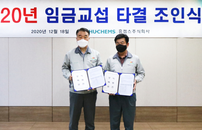 ▲18일 휴켐스 여수공장 대회의실에서 신진용 사장(왼쪽)과 박종태 노조위원장이 올해 임금협상 합의서에 사인한 후 기념촬영을 하고 있다. (사진제공=휴켐스)