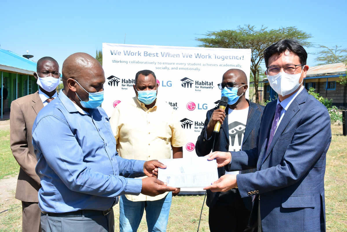 ▲LG전자가 한국해비타트와 함께 주거 취약계층을 위한 '희망마을' 사업을 펼친다. 15일 케냐 마차코스에 위치한 쿰비 초등학교에서 LG전자 김사녕 케냐법인장(오른쪽)이 쿰비 초등학교 이사회 알바나스 회장에게  '희망마을' 사업을 위한 건축 도면을 전달하고 있다. (사진제공=LG전자)