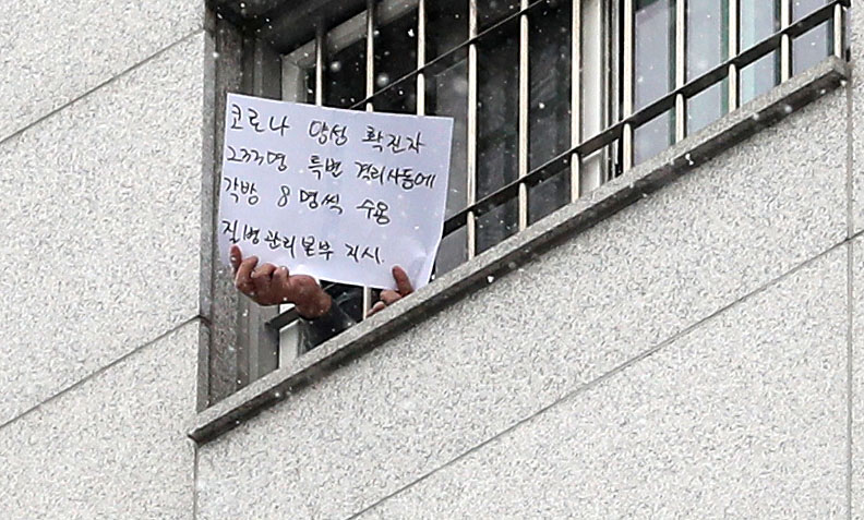 ▲대규모 집단 감염이 발생한 서울 동부구치소에서 233명이 추가 확진돼 누적 확진자가 761명으로 집계된 29일 서울 송파구 동부구치소에서 한 수용자가 자필로 쓴 글을 취재진에게 보여주고 있다. 종이에는 '코로나 양성 확진자 233명 특별 격리사동에 각 방 8명씩 수용, 질병관리본부 지시'라고 적혀있다.  (뉴시스)