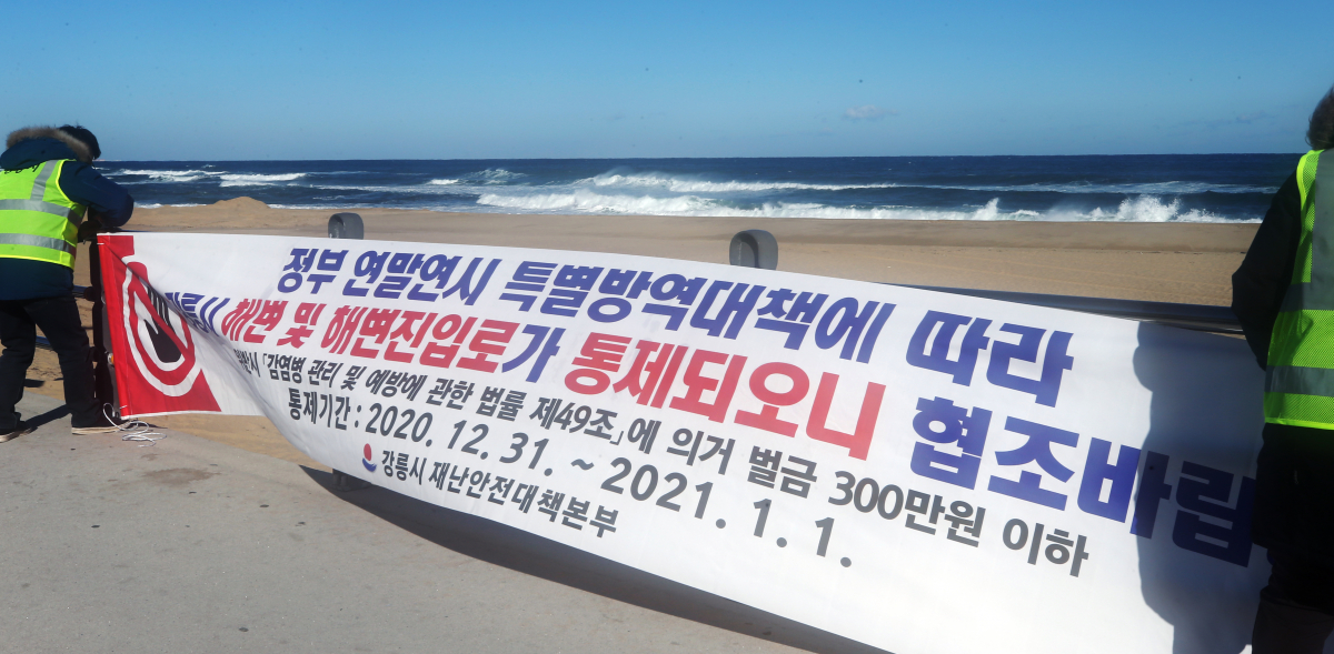 ▲새해를 하루 앞둔 31일 오후 강원 강릉시 공무원들이 해맞이 관광객들이 몰리면서 코로나19가 확산하는 것을 막기 위해 정동진 해변 주변에 안내 현수막을 내걸고 있다. (연합뉴스)