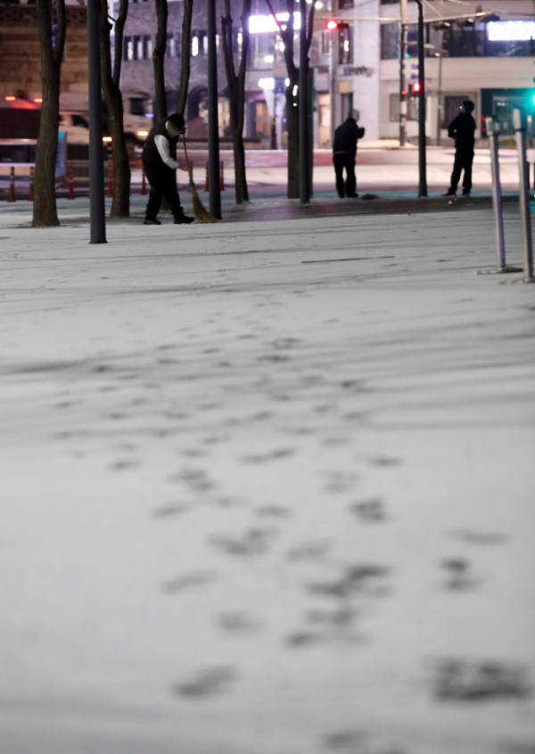 ▲밤사이 눈이 내린 18일 오전 서울 종로구 한 건물 앞에서 관계자들이 쌓인 눈을 쓸고 있다.  (연합뉴스)