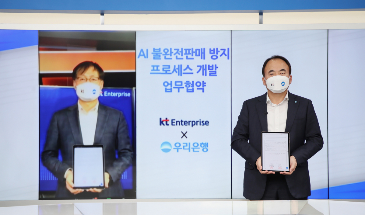 ▲우리은행은 지난 27일 KT그룹과 각 사가 마련한 화상회의실에서 온택트 방식으로 ‘AI 불완전판매 방지 프로세스 개발 업무협약’을 체결했다.심상형(오른쪽) 우리은행 투자상품전략단 부행장과 김준근(왼쪽) KT그룹 Enterprise 부문 전무가 기념촬영을 하고 있다. (사진제공=우리은행)