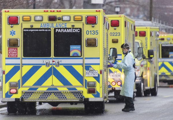 ▲지난달 28일(현지시간) 캐나다 몬트리올의 한 병원 밖에 늘어선 구급차들 옆에 한 의료인이 서 있다. 몬트리올/AP연합뉴스