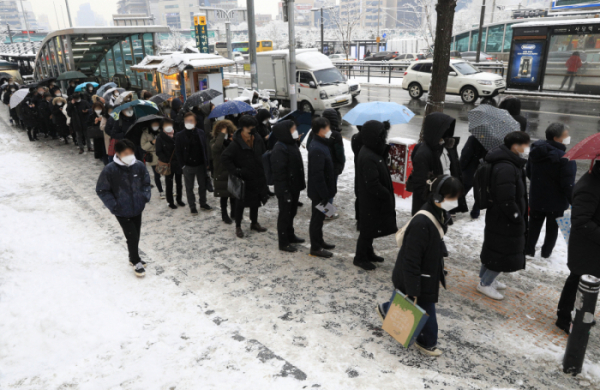 ▲서울 지역에 눈이 내리고 있는 12일 오후 서울 동작구 사당역 인근에서 시민들이 버스를 탑승하기 위해 길게 줄을 서 있다.  (뉴시스)