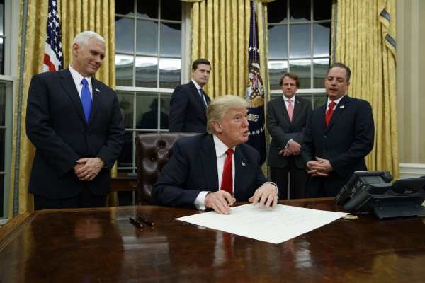 ▲도널드 트럼프(가운데) 미국 대통령이 2017년 1월 20일 백악관 집무실에서 취임 후 첫 행정명령에 사인하고 있는 모습. 워싱턴D.C/AP뉴시스
