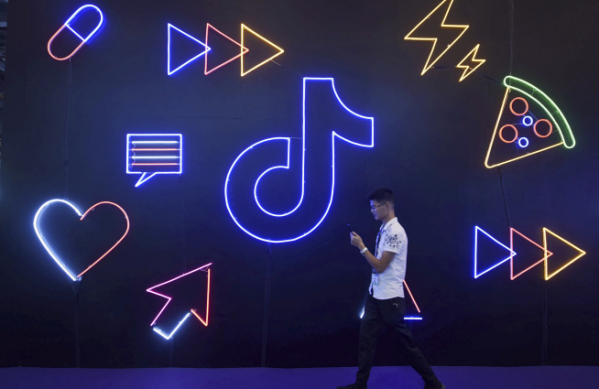 ▲중국 항저우에서 2019년 10월 18일 한 남성이 바이트댄스의 동영상 공유 앱 더우인 로고 앞을 지나가고 있다. 항저우/AP뉴시스
