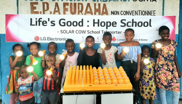 ▲LG전자가 최근 아프리카 콩고민주공화국의 동부지역에 있는 고마시의 초등학교를 대상으로 교육환경을 개선하고 전기 공급을 도와주는 'LG 희망학교' 프로젝트를 시작했다. 프라하(Furaha) 초등학교 학생들이 LG전자가 설치한 친환경 태양광 충전시스템 '솔라카우'를 이용해 충전한 휴대용 보조 배터리를 사용하며 기뻐하고 있다. (사진제공=LG전자)