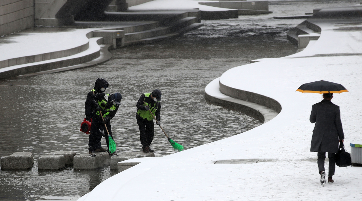 ▲눈이 내리는 16일 오후 서울 중구 청계천에서 환경미화원들이 징검다리의 눈을 쓸고 있다. (뉴시스)