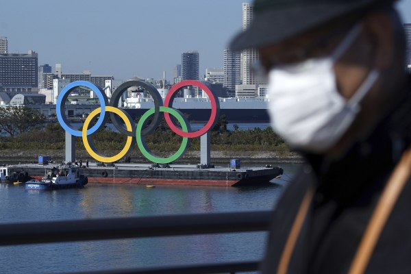 ▲지난해 12월 1일 마스크를 쓴 한 남성이 도쿄올림픽 오륜기 철조물 앞을 지나고 있다. 도쿄/AP뉴시스
