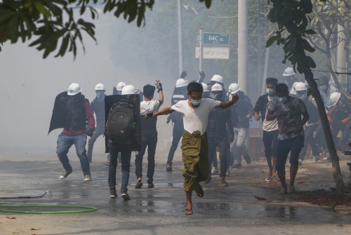 ▲미얀마 군부 쿠데타에 항의하는 시민들이 10일(현지시간) 무장 군경과 대치 도중 달려가고 있다. 만달레이/AP연합뉴스
