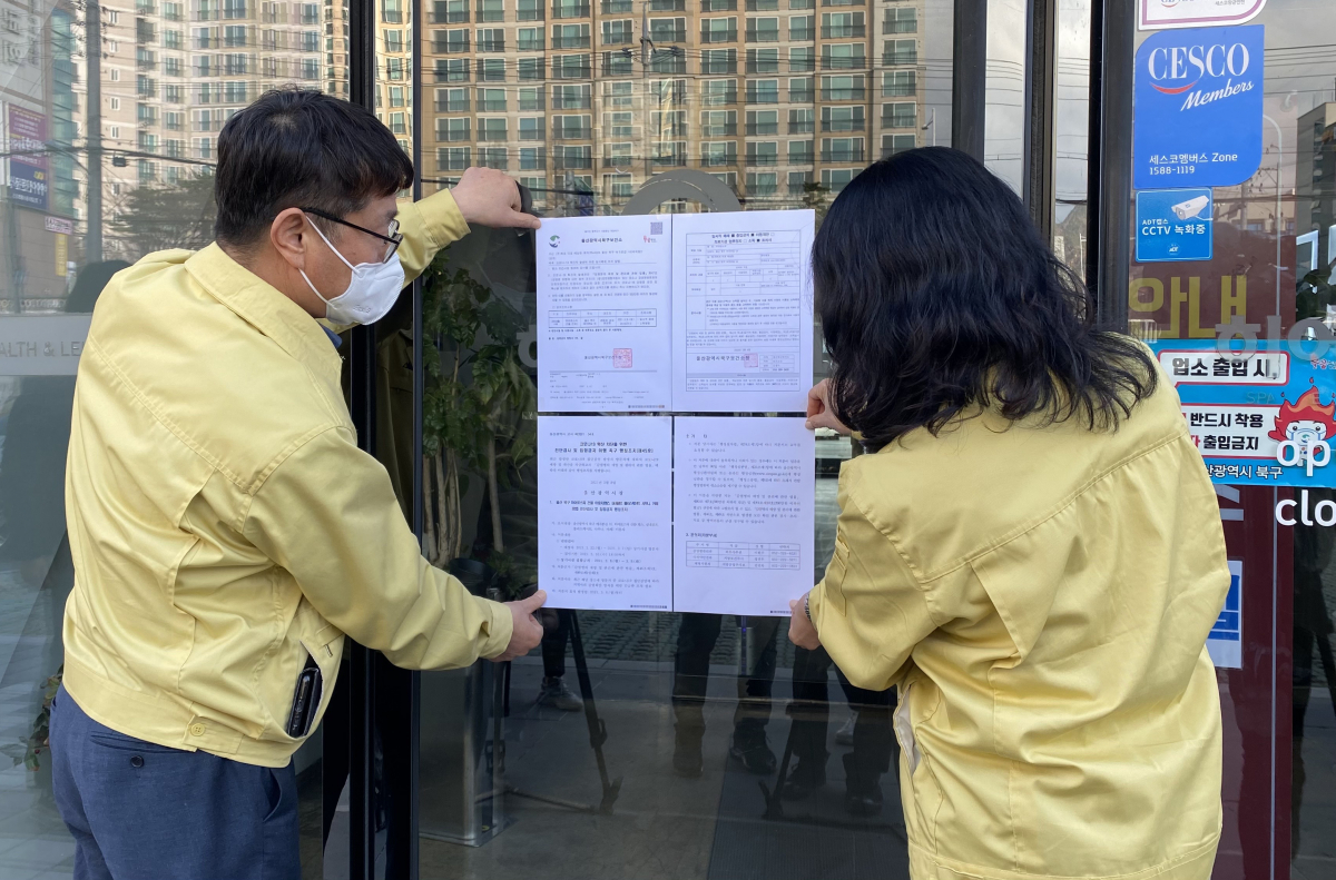 ▲8일 오후 울산시 북구 한 사우나 건물 출입문에 시 관계자가 행정조치 45호에 따른 이용자 진단 검사와 이틀간 건물 집합 금지를 명령하는 공문을 붙이고 있다. (출처=연합뉴스)