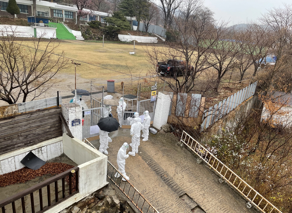 ▲27일 신종 코로나바이러스 감염증(코로나19) 환자가 무더기로 나온 인천시 강화군 길상면 폐교에서 내부에 있던 환자들이 병원으로 이동하기 위해 우산을 쓰고 교문을 나서고 있다. (연합뉴스)