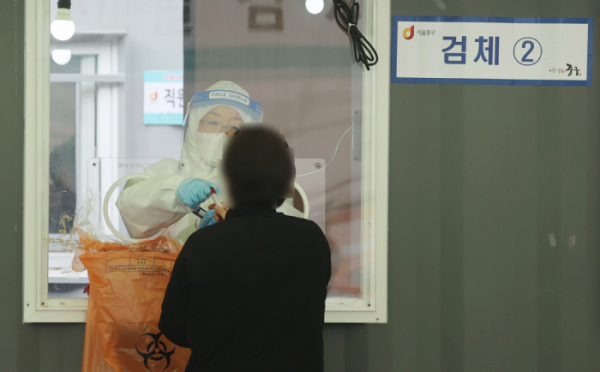 ▲12일 서울역 광장에 마련된 임시 선별검사소를 찾은 시민이 코로나19 검사를 받고 있다. (연합뉴스)