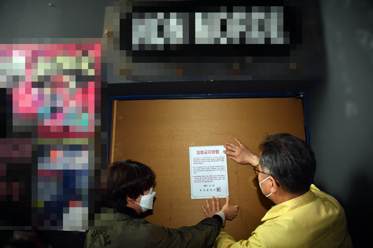 ▲부산지역 유흥시설 집합금지 조치 첫날인 12일 오후 부산진구청 공무원들이 서면의 한 업소 출입구에 집합금지 행정명령문을 부착하고 있다. 부산시는 지난 2일부터 적용 중인 사회적 거리두기 2단계를 12일부터 5월 2일까지 3주간 연장하고, 특히 이 기간 유흥시설 5종과 홀덤펍에 대해서는 집합금지 명령을 내렸다. (뉴시스)