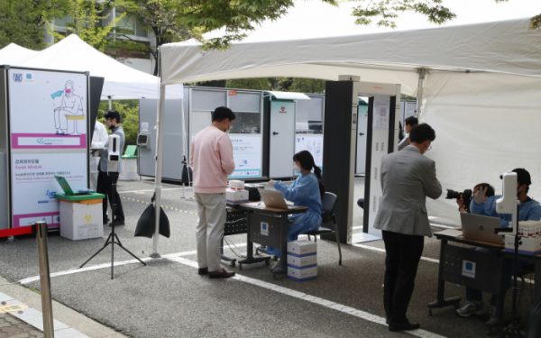 ▲2시간안에 검사결과가 나오는 코로나19'신속PCR검사'가 23일 서울 관악구 서울대 자연과학대 앞에서 시범적으로 실시됐다.  검사를 원하는 교직원들이 검진절차를 받고 있다.  (뉴시스)