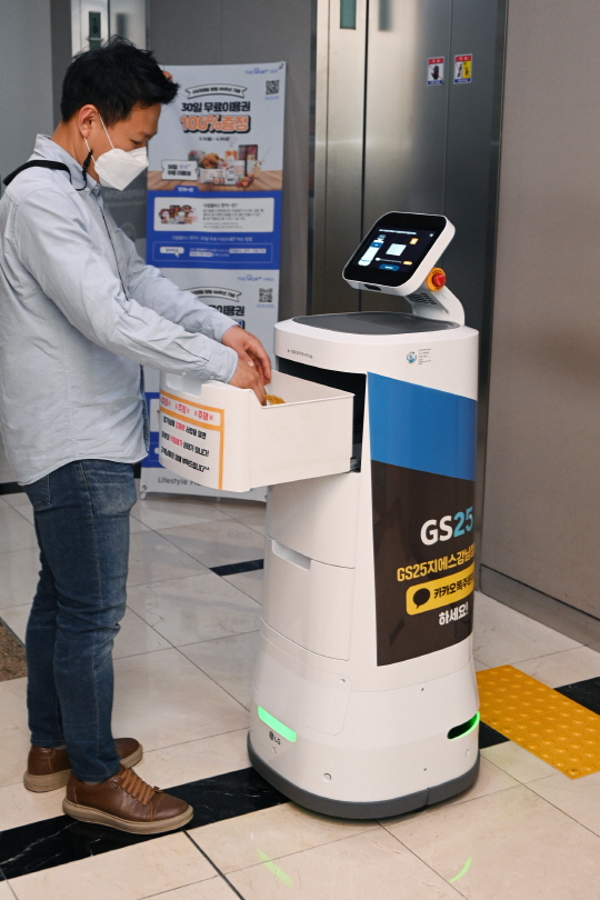 ▲LG전자가 GS리테일과 함께 실내 로봇 배달 서비스를 확대한다. 서울 강남구 역삼동에 위치한 GS타워에서 ‘LG 클로이 서브봇(LG CLOi ServeBot)’이 고객에게 편의점 주문 물건을 전달하고 있다.  (사진제공=LG전자)