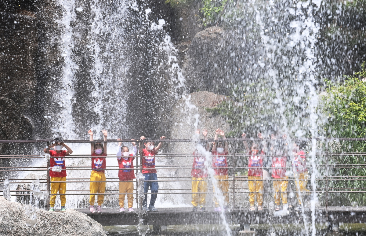 ▲초여름 날씨를 보인 12일 오후 경기도 안산시 노적봉인공폭포공원을 찾은 어린이들이 시원하게 쏟아지는 폭포수를 바라보며 즐거워하고 있다. (뉴시스)