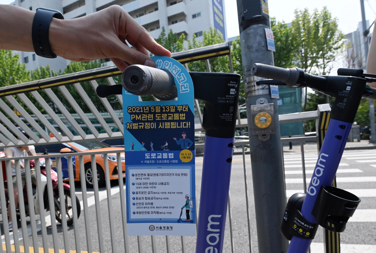 ▲전동 킥보드 규정이 강화된 첫날인 13일 오후 서울 영등포구 여의나루역 인근에서 영등포경찰서 교통과 소속 경찰이 주차된 전동킥보드에 개정된 도로교통법 안내문을 걸고 있다.  (연합뉴스)