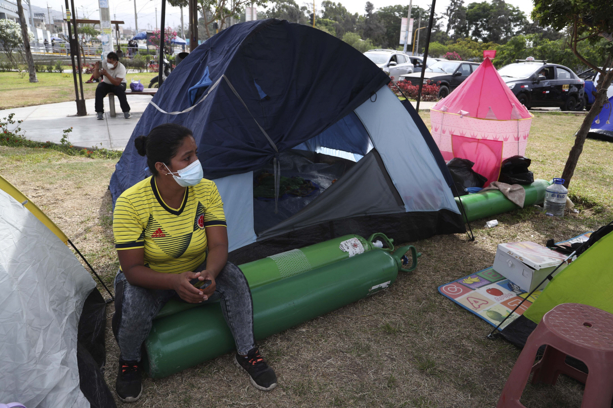 ▲페루 리마 인근 한 병원 앞에서 2월 27일(현지시간) 한 환자 가족이 빈 산소통 위에 앉아 검사 결과가 나오기를 기다리고 있다. 리마/AP뉴시스