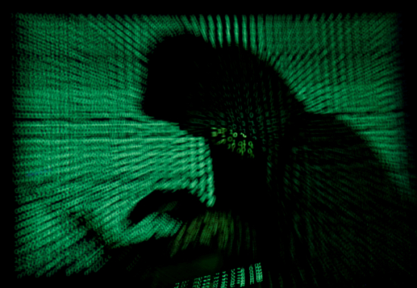 ▲사이버 코드를 배경으로 한 남자가 노트북 컴퓨터를 들고 있다. 로이터연합뉴스
